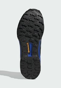 Čierna gumová podrážka s hlbokými vzormi; obsahuje modrý bočný pruh a viditeľné oranžové logo "Continental". Štruktúrovaný, robustný dizajn.