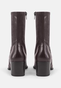 Bruine leren enkellaarsjes met een gestructureerd bovenwerk, een afgeronde neus en een blokhak. Voorzien van een rits aan de achterkant en een gladde afwerking.