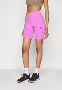 Shorts de sport taille haute fuchsia avec une texture lisse, présentant un détail de logo noir et un design sans coutures sur les côtés.