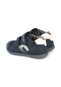 Scarpe in pelle blu navy con accenti bianchi, due cinturini in velcro, suola in gomma grigia e motivo a pois sul lato. Logo del marchio sul tallone.