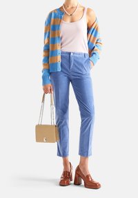 Randig kofta i blått och brunt, ljus linne-topp, blå skräddarsydda byxor, bruna klackskor med blockklack och en beige handväska med kedjetröjor.