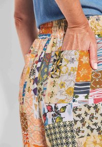 Multicolored patchwork broeken met bloemen- en geometrische patronen, elastische tailleband en zijzakken met een gestructureerde stofafwerking.