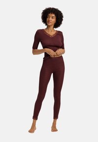 Bordeaux loungewear set met een korte mouwen top met kantafwerking en aansluitende legging met kantaccenten bij de enkels, vervaardigd uit een gestructureerde stof.