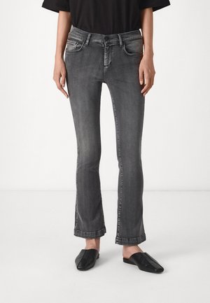 Grå denim flared jeans med fem lommer, subtil falming og en tettsittende livlinje. Brukt med svarte slip-on sko.