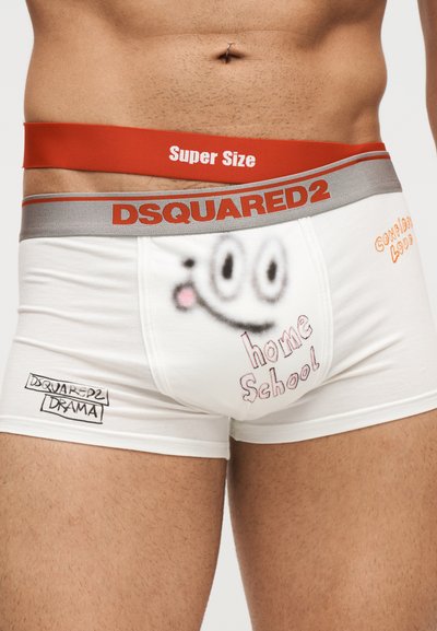 Ανδρική μέση που φοράει λευκά boxer DSQUARED2 με γκρι και κόκκινη μέση και καρτούν πρόσωπο, κείμενο που λέει "home School" και "Super Size".