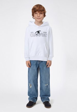 Weißer Kapuzenpullover mit "CHAMPION"-Logo, kombiniert mit hellblauen, abgenutzten Jeans mit weitem Bein und schwarzen Turnschuhen. Lässige Sportbekleidung.