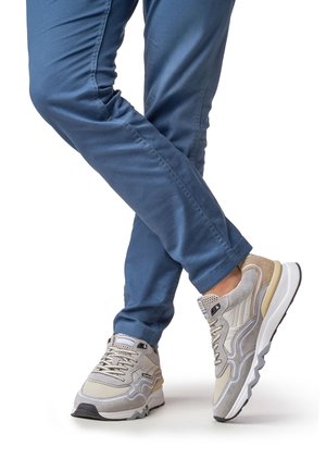 Hellgraue und beigen Sneaker aus Mesh- und Veloursledermaterialien, mit einzigartigem wellenförmigem Design, gepolstertem Kragen und strukturierter Gummisohle.