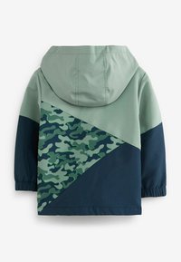 Huvtröja med en ljusgrön överdel, mörk marinblå underdel och ett camouflagemönster på baksidan i olika nyanser av grönt.