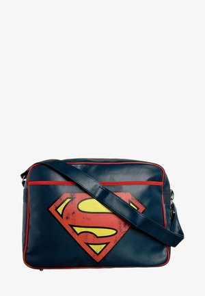 Marineblaue Tasche aus Kunstleder mit roten Akzenten, vorne ein gelb-rotes Superman-Logo. Mit abnehmbarem Schultergurt.