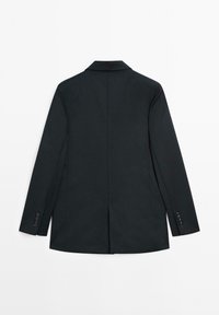 Zwarte op maat gemaakte blazer gezien van achteren, met lange mouwen, een inkepingkraag en een centrale achterzoom.