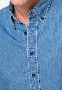 Lichte blauwe denim blouse met knopen, met een gestructureerde stof, puntige kraag en donkerbruin knopen langs de voorbies.