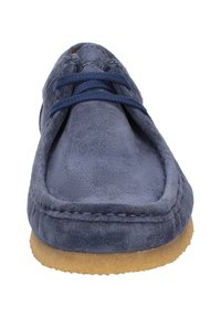Chaussure en daim bleu avec un bout arrondi, un laçage, et une semelle en caoutchouc contrastante couleur tan. Présente des finitions avec des coutures en bordure.