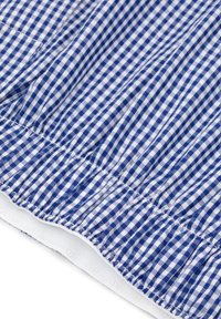 Niebiesko-biały materiał w kratkę gingham z marszczeniami na dolnym końcu. Gładkie białe wykończenia wzdłuż krawędzi.