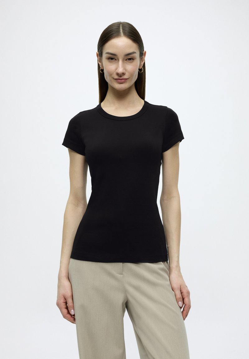 Μαύρο t-shirt με κοντά μανίκια από μαλακό ύφασμα, με στρογγυλή λαιμόκοψη και εφαρμοστή γραμμή. Χωρίς σχέδια ή εμφανή εξαρτήματα.