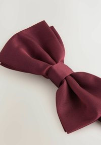 Nœud papillon bordeaux en satin texturé ; présente un nœud central avec des extrémités drapées et pointues. Fini lisse avec un léger éclat.