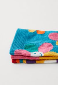 Bunte Socken gestapelt: blau mit großen Punkten, pink, lila und gelbe Streifen. Weiches Strickmaterial mit verspielten Mustern.