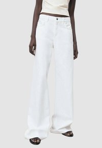 Wide-leg white jeans made of denim, featuring a high waist and front pockets, with a clean design and no visible embellishments.