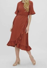 Abito color ruggine con un tessuto strutturato, maniche corte a campana e orlo arricciato. Caratterizzato da un design avvolgente e una vita con cintura.