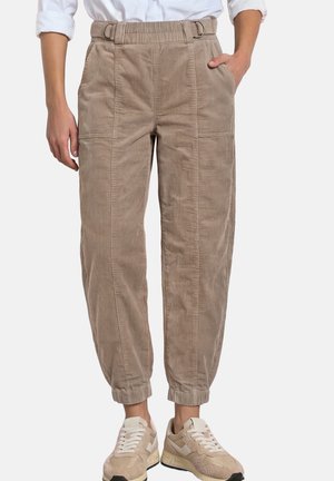 Beige Cordhosen mit elastischen Bündchen, Seitentaschen und einem Doppelring-Gürtel, getragen mit beige-weißen Sneakern.