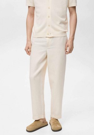 Light beige linen trousers with a relaxed fit, featuring a smooth texture and a simple design, paired with brown slip-on shoes.