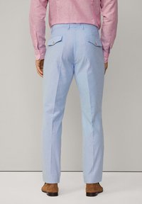 Jasnoniebieskie spodnie w paski z dwiema tylnymi kieszeniami, dopasowany krój, pas z szlufkami na pasek oraz delikatnie teksturowana tkanina.