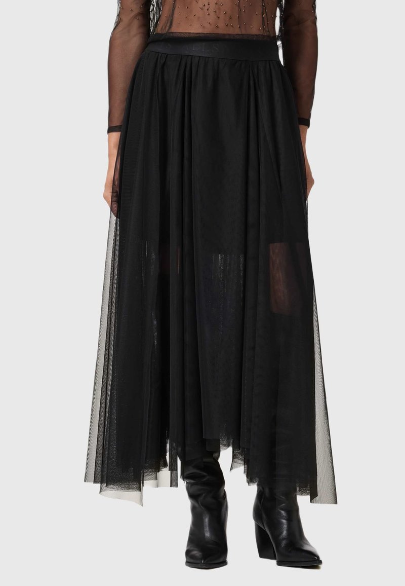 Jupe maxi en tulle noir au design fluide, dotée d'une taille ajustée et de couches de tissu semi-transparent. Associée à des bottes noires montantes.