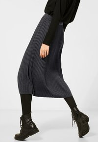 Jupe midi côtelée grise avec une coupe décontractée, dotée d'un tissu texturé et d'une taille élastique, associée à des bottines à lacets noires.