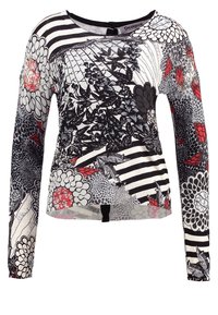 Långärmad kvinnotopp med svarta, vita och röda blommiga samt randiga abstrakta mönster, samt spetsdetaljer på ärmarna.