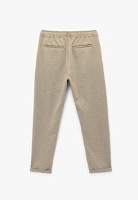 Beige Jogginghosen aus strukturiertem Stoff, mit elastischem Bund, zwei Gesäßtaschen und tapered Beinen mit Bündchen.