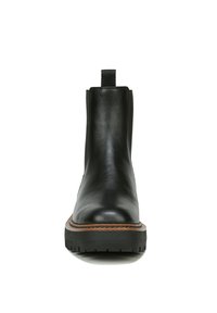 Stivale alla caviglia in pelle nera con pannelli elastici laterali, suola piatta in gomma e un dettaglio di cucitura marrone a contrasto lungo il bordo della suola.