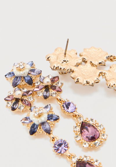 Σκουλαρίκια σε χρυσό τόνο με μοβ και μπλε πολύτιμους λίθους, λευκές πέρλες και διάφανα κρύσταλλα τοποθετημένα σε σχήματα λουλουδιών και σταγόνας.