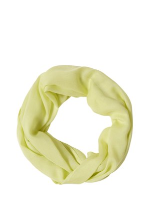 Lachende vrouw met bruin haar, die een wit mouwloos topje en een lichtgroene sjaal draagt tegen een effen achtergrond.