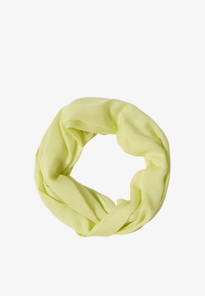 Femme souriante aux cheveux bruns portant un haut blanc sans manches et une écharpe vert clair sur un fond uni.