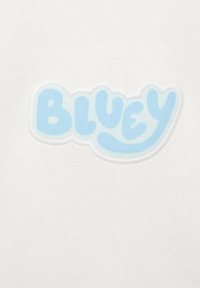 Tessuto bianco con il logo "BLUEY" in azzurro chiaro, bordato da un contorno bianco. La texture sembra liscia e morbida.