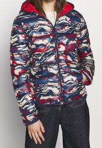 Gewatteerde jas met een camouflagepatroon in marineblauw, crème en rood. Gemaakt van glanzende stof met een ritssluiting aan de voorkant en capuchon. Getextureerd, doorgestikt ontwerp.