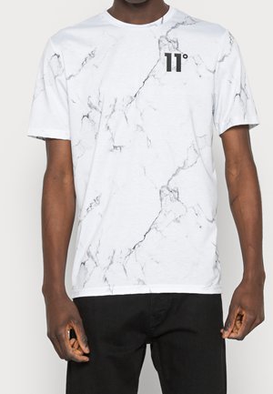 T-shirt blanc à manches courtes avec un motif marbré accentué de gris, présentant un petit logo noir sur la poitrine et une coupe décontractée.