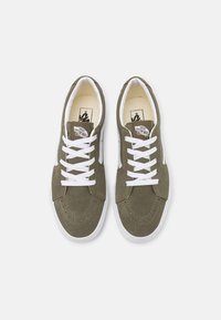 Olivengrønne ruskind sneakers med hvide snørebånd, en rund tå og hvide gummisåler. Har et klassisk Vans-logo på tungen.