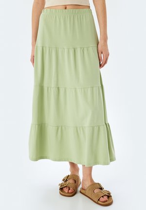 Jasnozielona, warstwowa spódnica maxi z elastycznym pasem. Miękka, gładka tkanina o swobodnym kroju. Uzupełniona brązowymi sandałami z klamrami.