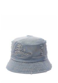 Cappello a secchiello in denim chiaro con bordi sfrangiati, design di teschio ricamato e una finitura leggermente strutturata. Forma rotonda con una larga visiera.