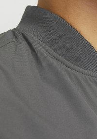 Gray jacket collar with a textured fabric. Smooth body fabric, featuring visible stitching and seam details, enhancing the overall design.