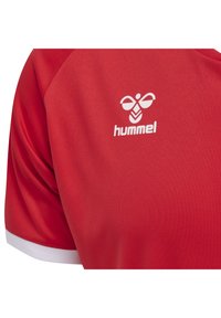 Röd sporttröja i slät tyg med en vit "hummel"-logotyp på bröstet och kontrasterande vit kant på ärmarna.