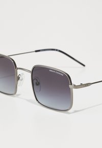 Sunglasses med en metallisk silverram, fyrkantiga linser med en gradation från mörkgrått till ljusare grått, och klara nässkydd.