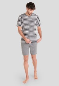 Camiseta de hombre de manga corta a rayas grises con cuello en V y bolsillo, combinada con pantalones cortos de algodón grises. Ajuste casual, tejido ligero, diseño relajado.