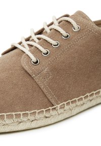 Brauner Leinenschuh mit strukturiertem Stoff, runder Zehenpartie, kontrastierenden beigen Schnürsenkeln, Metallösen und einem juteähnlichen Stickmuster um die Sohle.