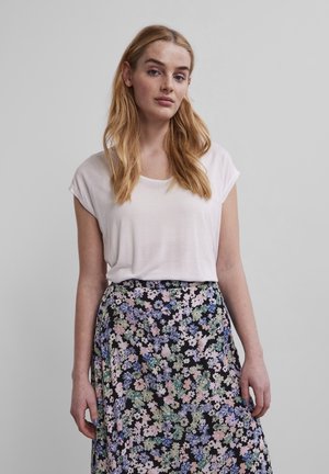 Camiseta de manga corta blanca combinada con una falda negra con un patrón floral colorido. Textura de tela suave, corte relajado y estilo informal.