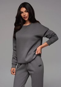 Sudadera gris y pantalones de chándal a juego, hechos de material suave, con un escote redondeado, puños de canalé y sutiles acentos de logo.