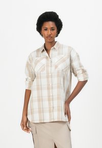 Μπεζ και λευκό πουκάμισο με καρό σχέδιο, κλείσιμο με κουμπιά, δύο τσέπες στο στήθος και μανίκια που είναι σηκωμένα. Λείο ύφασμα με χαλαρή εφαρμογή.