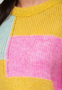 Gebreide pullover in geel, roze en lichtblauw met een boxy ontwerp, geribde halslijn en afwisselende textuurstrepen door het hele stuk.