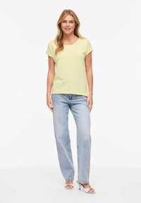 Ανοιχτό κίτρινο κοντομάνικο μπλουζάκι με στρογγυλή λαιμόκοψη, συνδυασμένο με ανοιχτό μπλε παντελόνι φαρδιάς γραμμής και πέδιλα με ανοιχτά δάχτυλα. Απλό και καθημερινό στυλ.