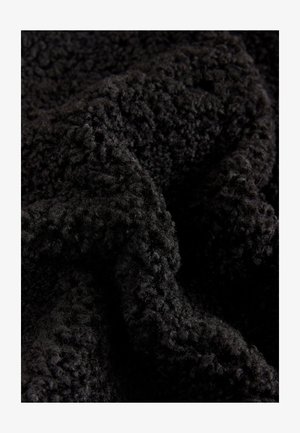Črno puhasto blago z teksturirano, izbočeno površinsko vzorcem, ki vsebuje mehka, neenakomerna in gosta vlakna ter daje prijeten, vabljiv videz.